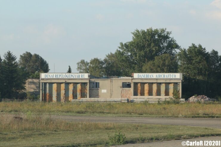 View of a building from across a grassy patch of land at Tököl Airbase