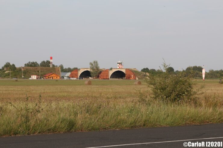 View of the aircraft hangars at Tököl Airbase from across a road and grassy field
