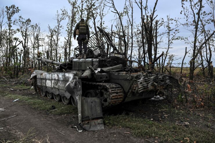 Ukrainian soldier standing on top of a destroyed Russian tank. 