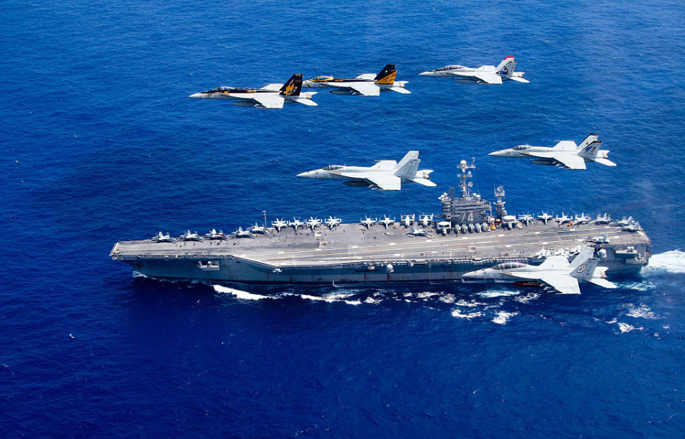 Five McDonnell Douglas F/A-18 Hornets flying over the USS John C. Stennis (CVN-74)