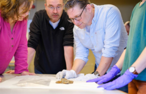 Archaeologists looking at a Viking Age sword placed on a white tabletop