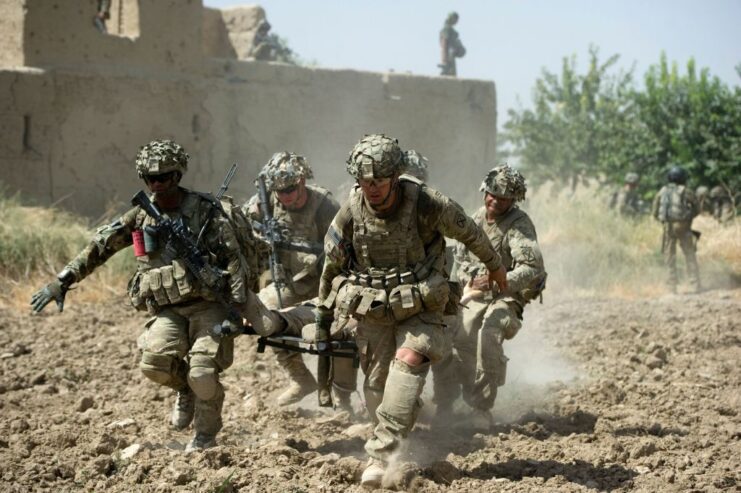 Four US Army soldiers carrying a wounded comrade on the outskirts of a village