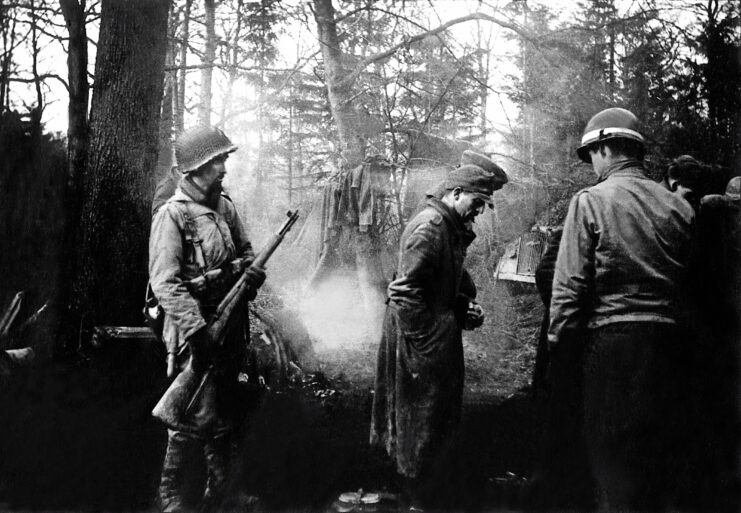 An American soldier with German POWs on Hürtgen Forest during the Battle of the Bulge.