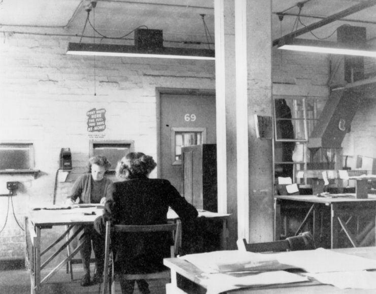 Two women sitting at a table writing. 