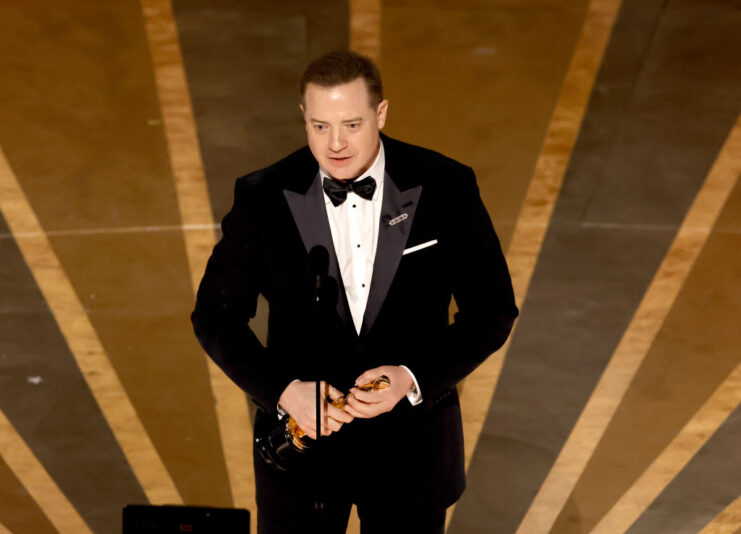 Brendan Fraser speaking into a microphone on stage