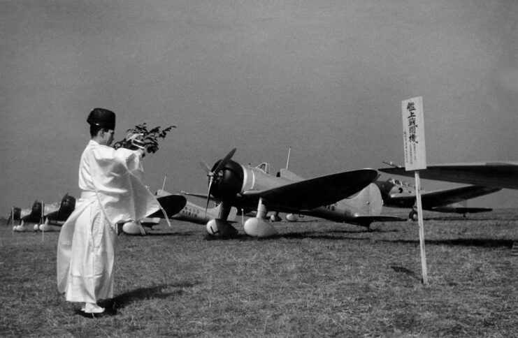 Fighter plane Mitsubishi A5M being blessed by a shinto priest with the twig of a holy tree.