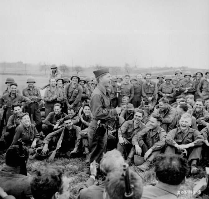 American troops sitting around Mickey Rooney