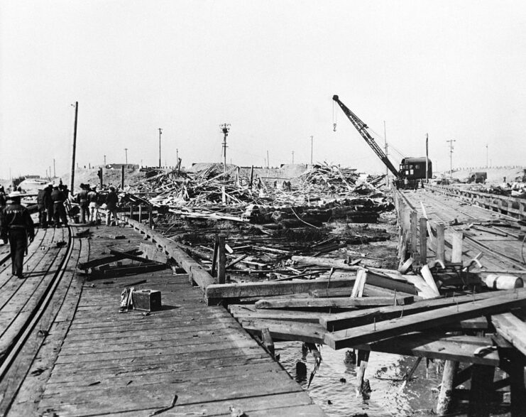 Sailors standing on the remains of a wooden pier