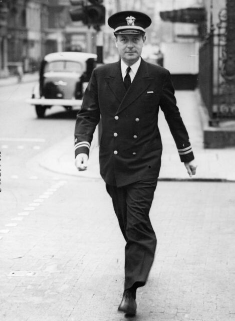 Robert Montgomery walking down a street in his US Navy uniform