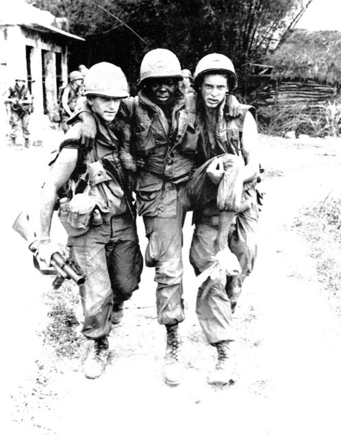 Two US soldiers helping another walk