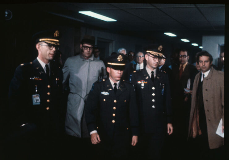 Kenneth Raby, William Calley and Jeffrey Scribner walking past a group of men