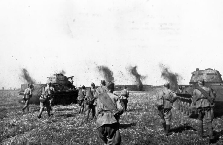 Red Army troops running in a field with T-34 tanks