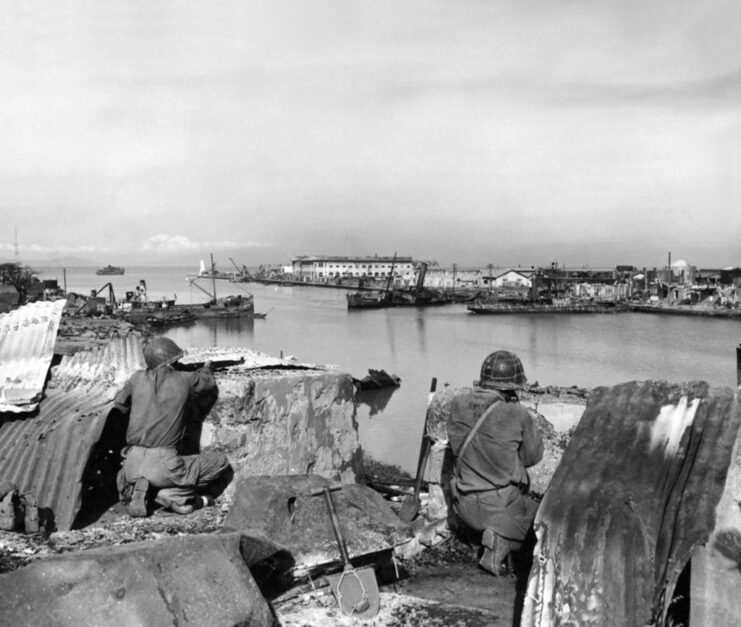 Two American soldiers aiming their weapons across the Pasig River, in the Philippines