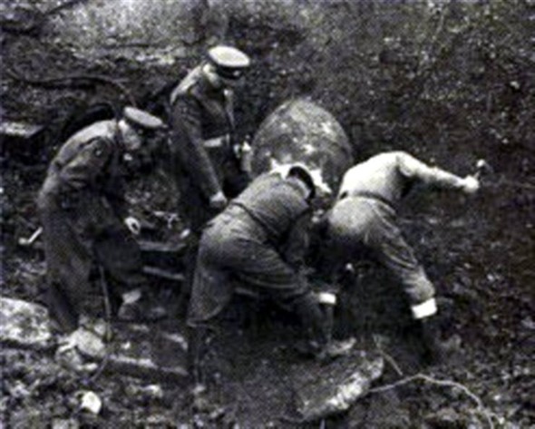 Four bomb disposal technicians standing around an explosive