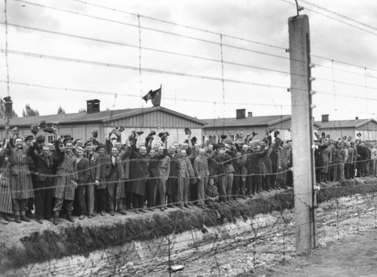 Prisoners of Dachau concentration camp cheering from behind a fence