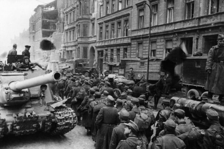 German prisoners of war (POWs) walking by a tank in the middle of a street