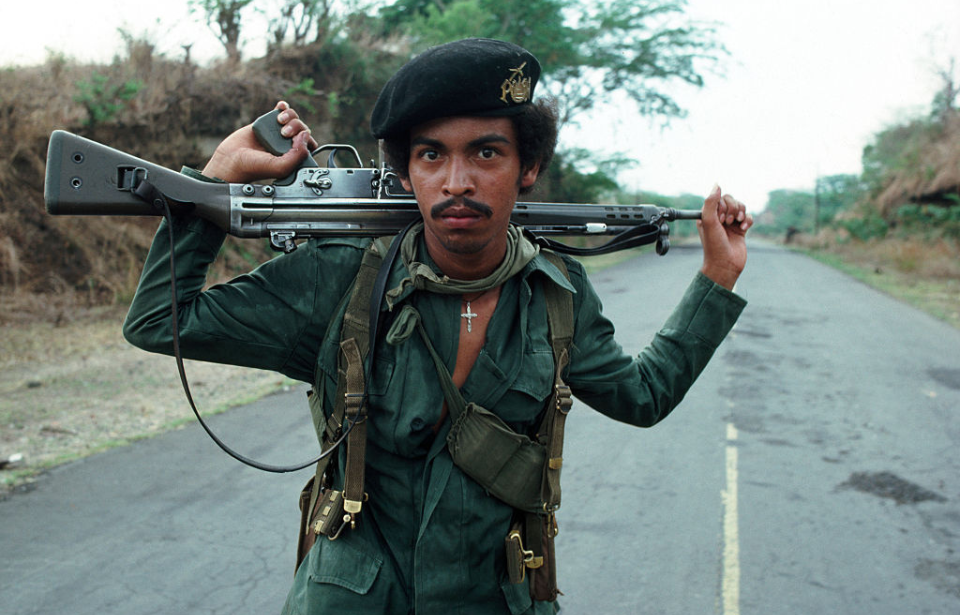 El Salvadorian guerrilla standing in the middle of a roadway with a Heckler & Koch G3 resting on his shoulders