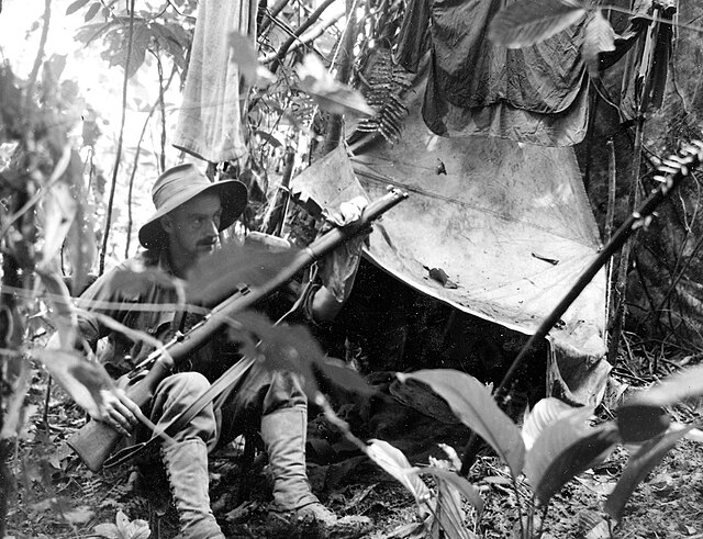 Australian soldier cleaning his rifle in the jungle