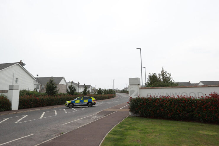 Police vehicle positioned near the entrance sign to the Rivenwood housing development in Newtownards, County Down, Northern Ireland