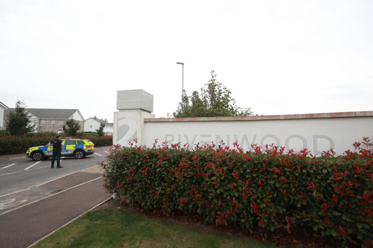 Police officer and vehicle positioned near the entry sign to the Rivenwood housing development in Newtownards, County Down, Northern Ireland