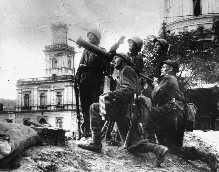 Five Polish soldiers standing with an anti-aircraft gun, looking toward the sky