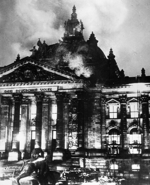 Firefighters standing outside of the Reichstag, which is on fire