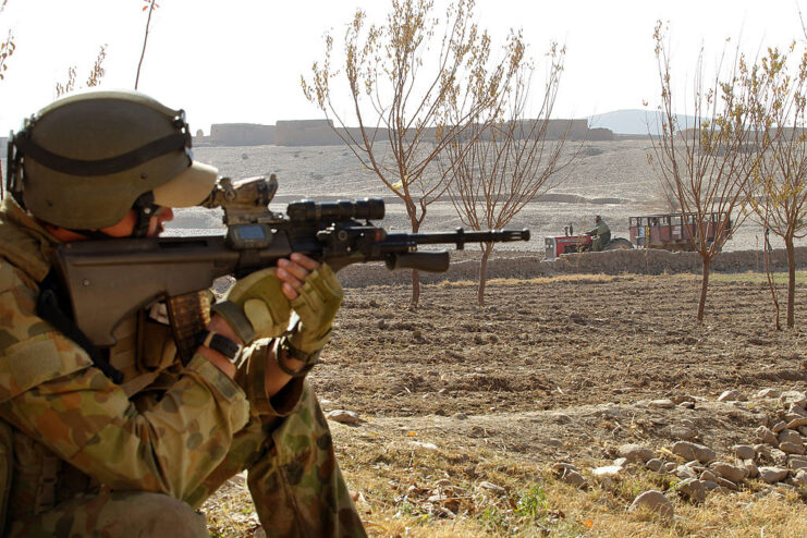 Soldier aiming his rifle in the middle of a desert area