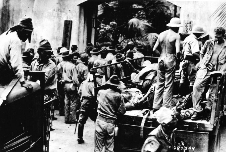 American and Filipino prisoners of war (POWs) standing together near a building