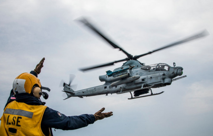 Crewman waving a Bell AH-1Z Viper toward the flight deck of the USS Kearsarge (LHD-3)