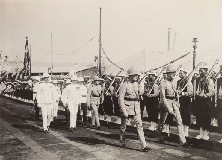 Police officials walking in front of British South Africa Police (BSAP) members who are standing at attention