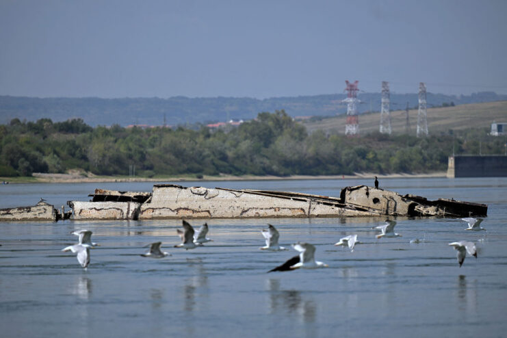 Sea gulls flying around a partially-submerged shipwreck in the Danube