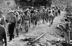 American and Filipino prisoners of war (POWs) being led through a village