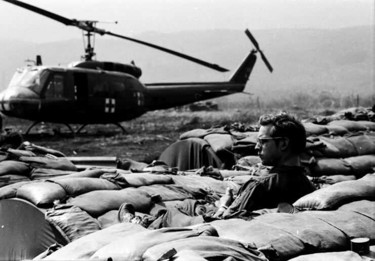 MEDEVAC crewman resting near a Bell UH-1 Huey