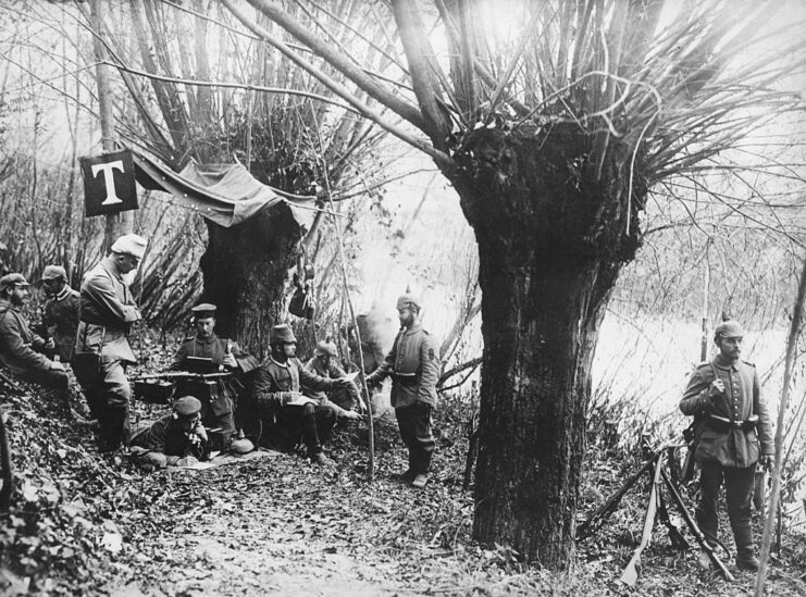 German troops standing at a telephone station set up in the middle of a wooded area