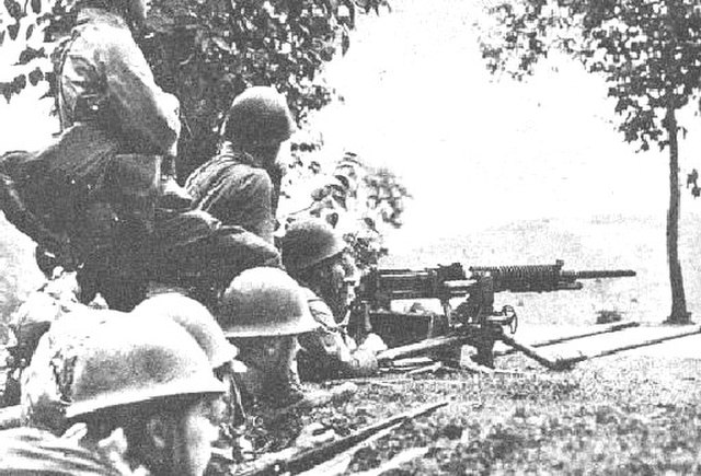 Japanese soldiers sitting low while aiming their weapons