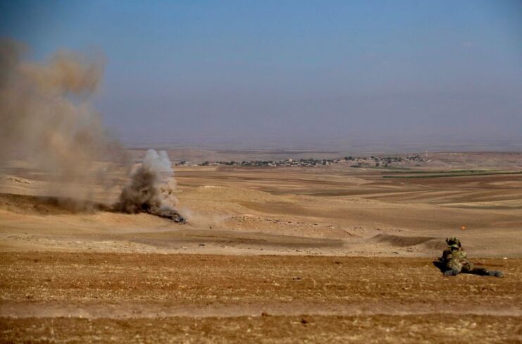 Member of the Syrian Democratic Forces (SDF) lying on his stomach in the middle of the desert