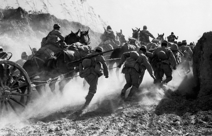 Japanese troops running through a divot in the earth