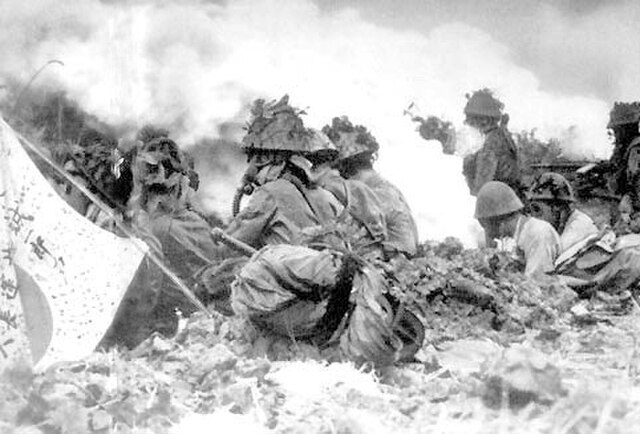 Japanese soldiers crouched while wearing gas masks