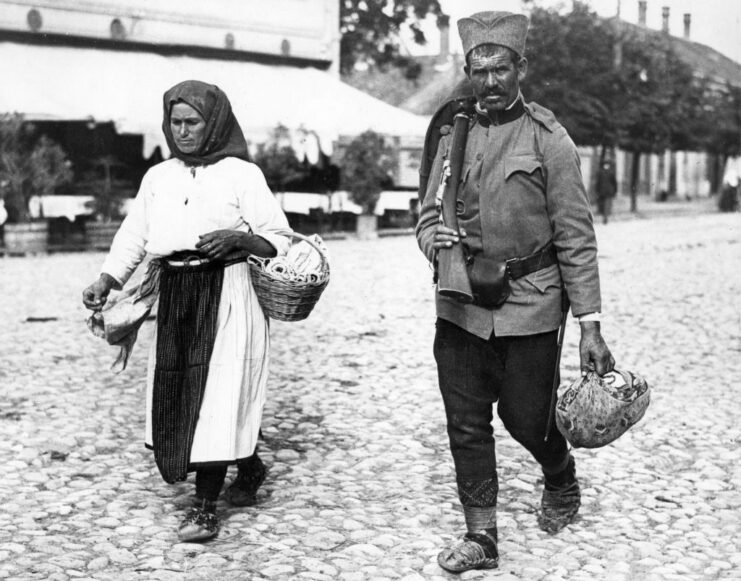 Serbian soldier walking down a street with his wife