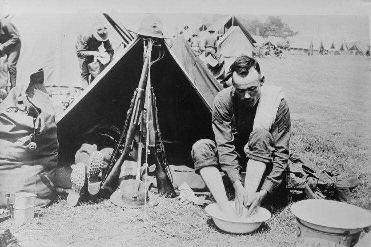 US Marine washing his feet while sitting outside of a tent