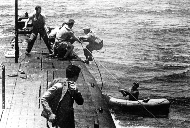 Crewmen aboard the USS Tang (SS-306) helping lift sailors out of a life raft