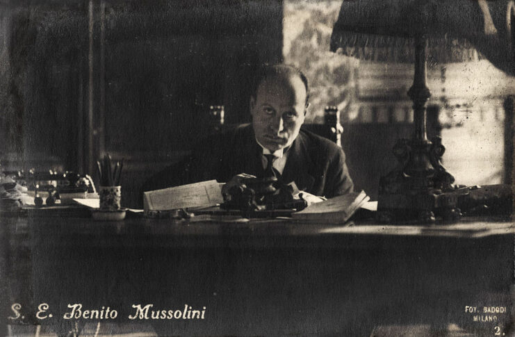 Benito Mussolini sitting at his desk