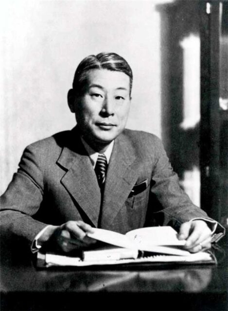 Chiune Sugihara sitting at a table, with a book in his hands