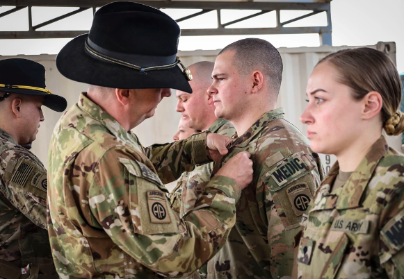 Four 82nd Airborne Division paratroopers receiving the combat medic badge from two superiors