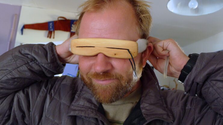 Man wearing wooden Inuit sunglasses.