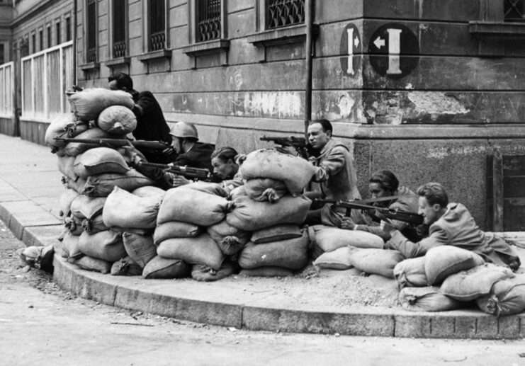 Six Italian partisans aiming weapons from behind a wall of sand bags