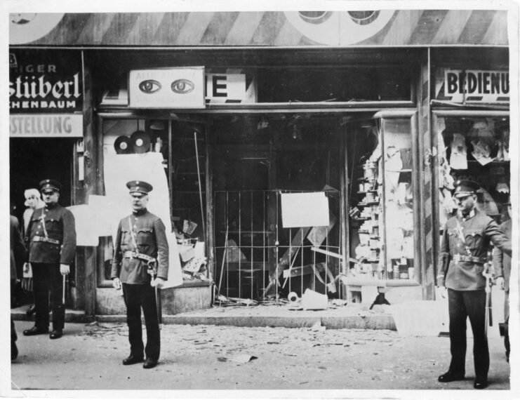 Police officers standing guard outside a store with a broken front window