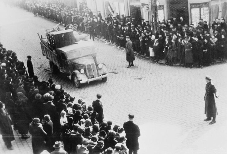 Crowd watching a truck drive down a street