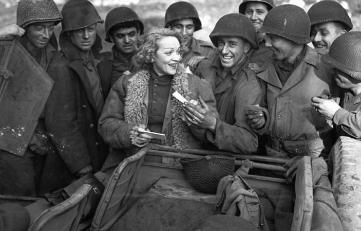 Marlene Dietrich standing with a group of soldiers