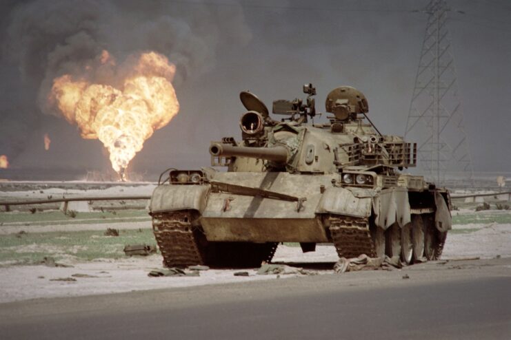 An abandoned Iraqi Soviet-made T-62 tank in front of a fire.